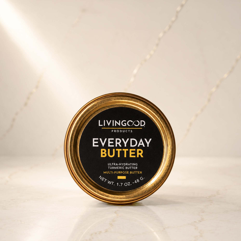 A round tin of Livingood Products Everyday Butter, featuring a black label with gold and white text, set on a light marble surface with a matching marble background.