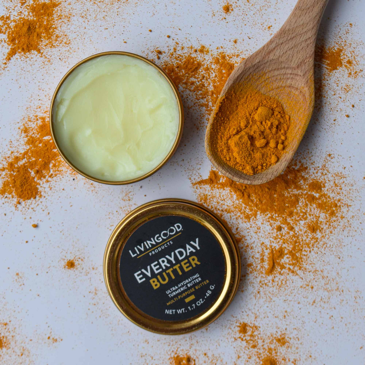 Everyday Butter tin on gray background with wooden spoon, and turmeric powder