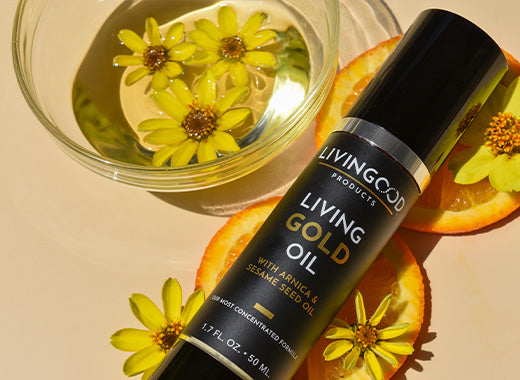 Living Gold Oil sitting on orange slices and yellow flowers