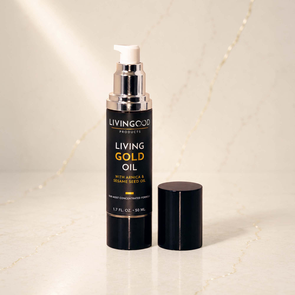 Living Gold Oil pump bottle with its cap off, displayed on a light marble surface with a soft-focus background.