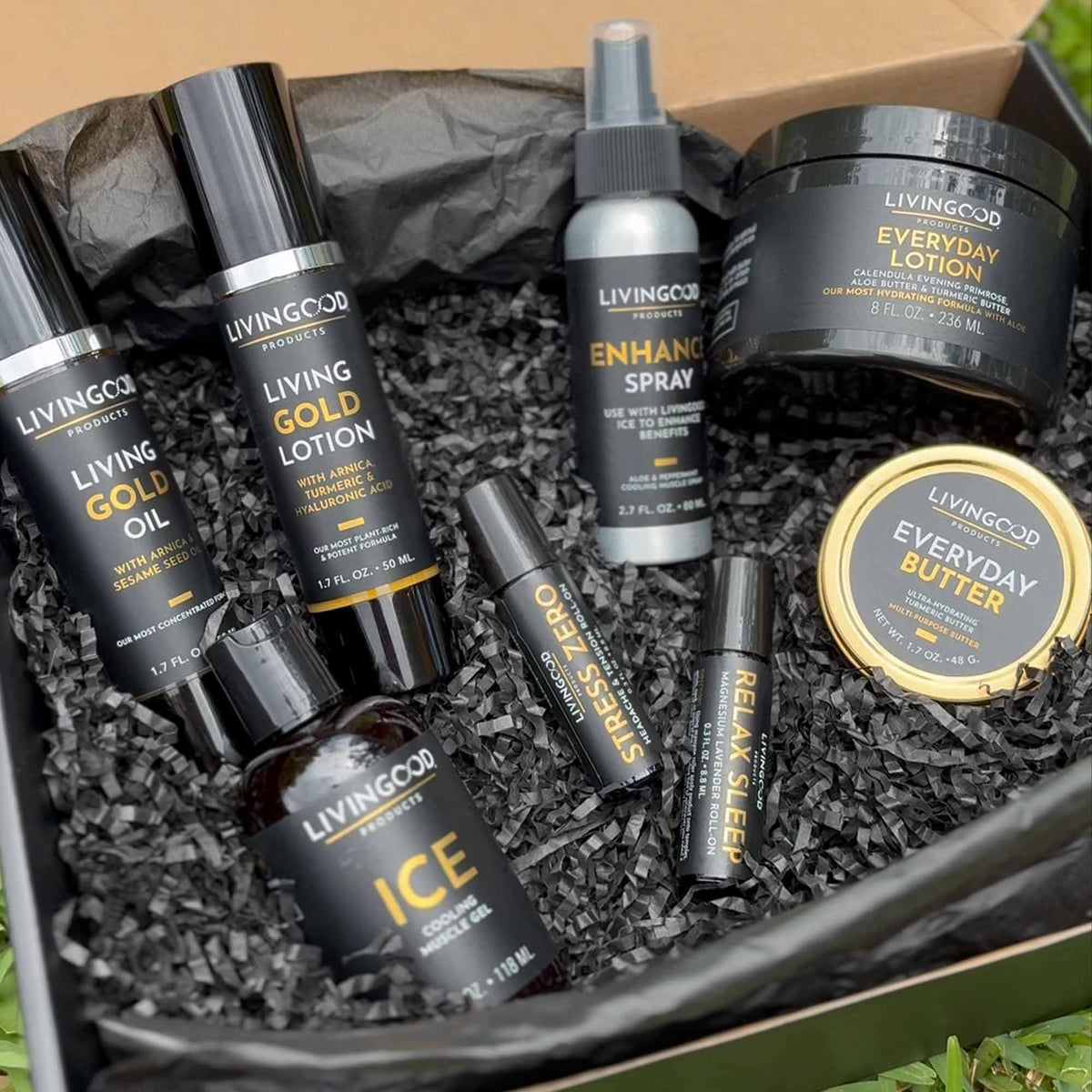 various Livingood Products in a box with black shipping material sitting on green grass.